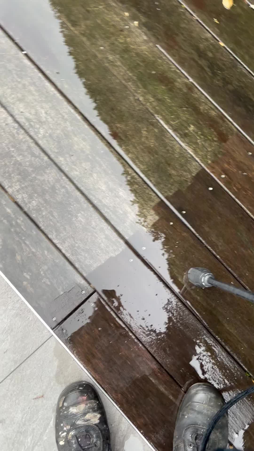 Pressure washing a grey, mossy timber deck back to rich brown boards
