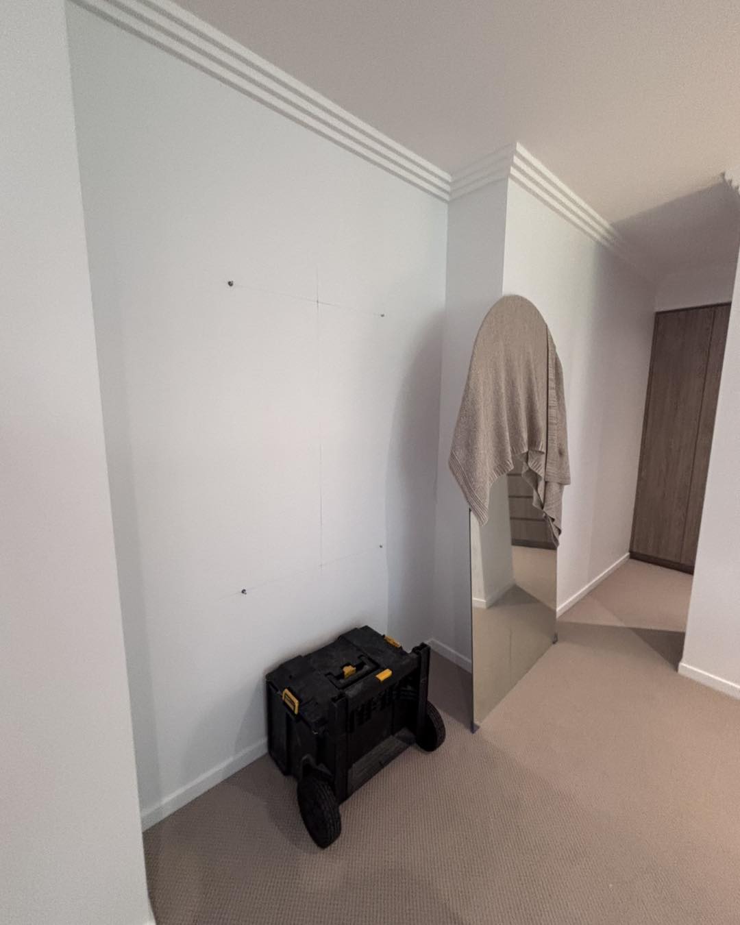 Before: a blank wall marked out for fixings, the mirror leaning against it under a towel