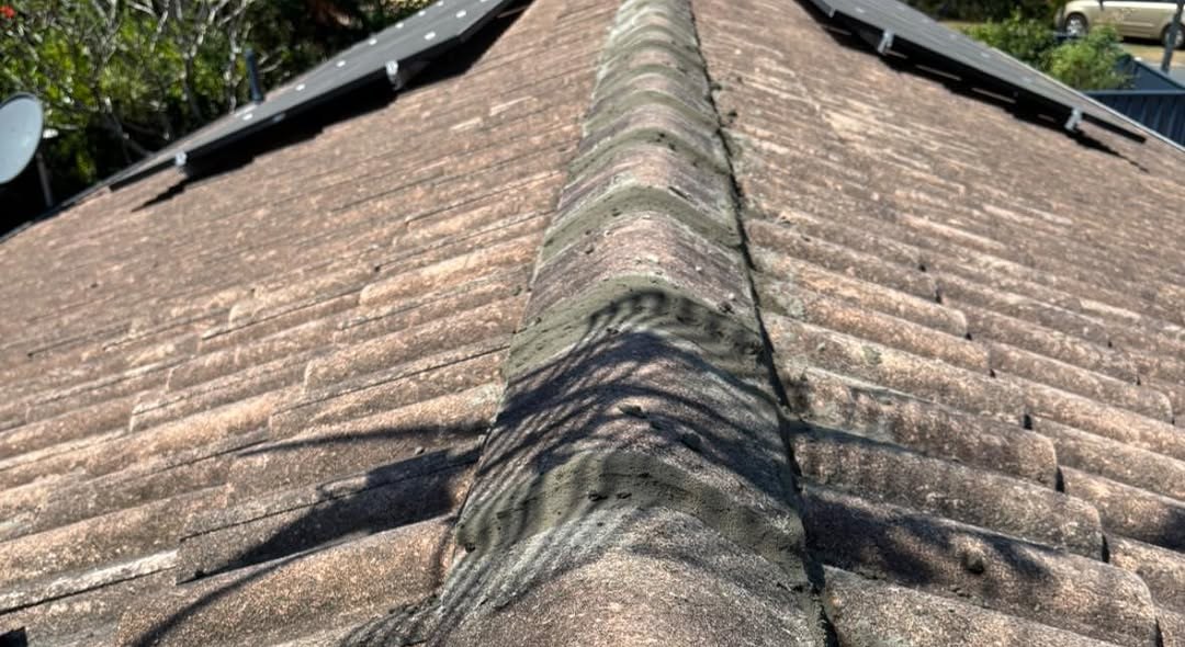 After: the ridge capping re-pointed with fresh mortar, solar panels on either side