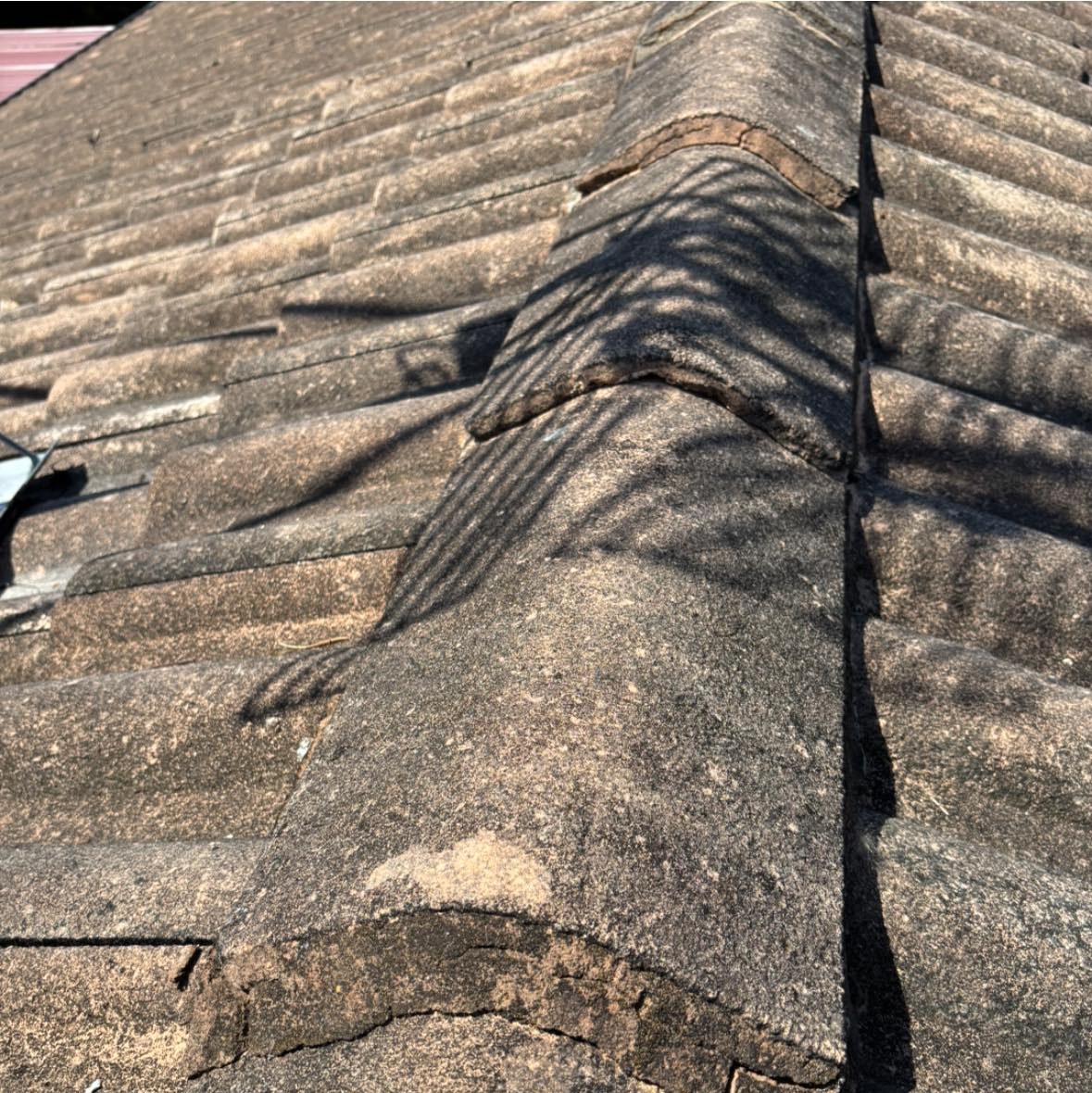 Before: cracked and crumbling mortar under the ridge capping of a tiled roof