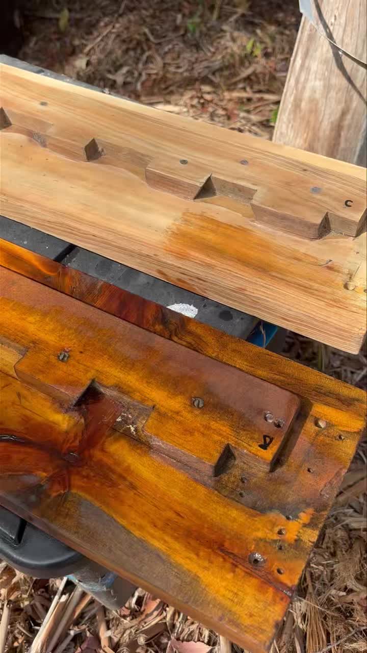 Two timber boards on a workbench, one raw and one freshly stained a deep orange